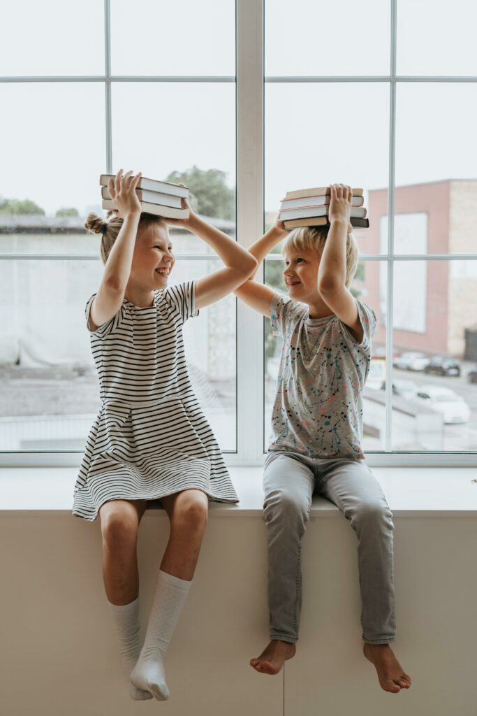 pexels-photo-5088188-5088188 Two happy children playing with books, embodying the joy of learning together.