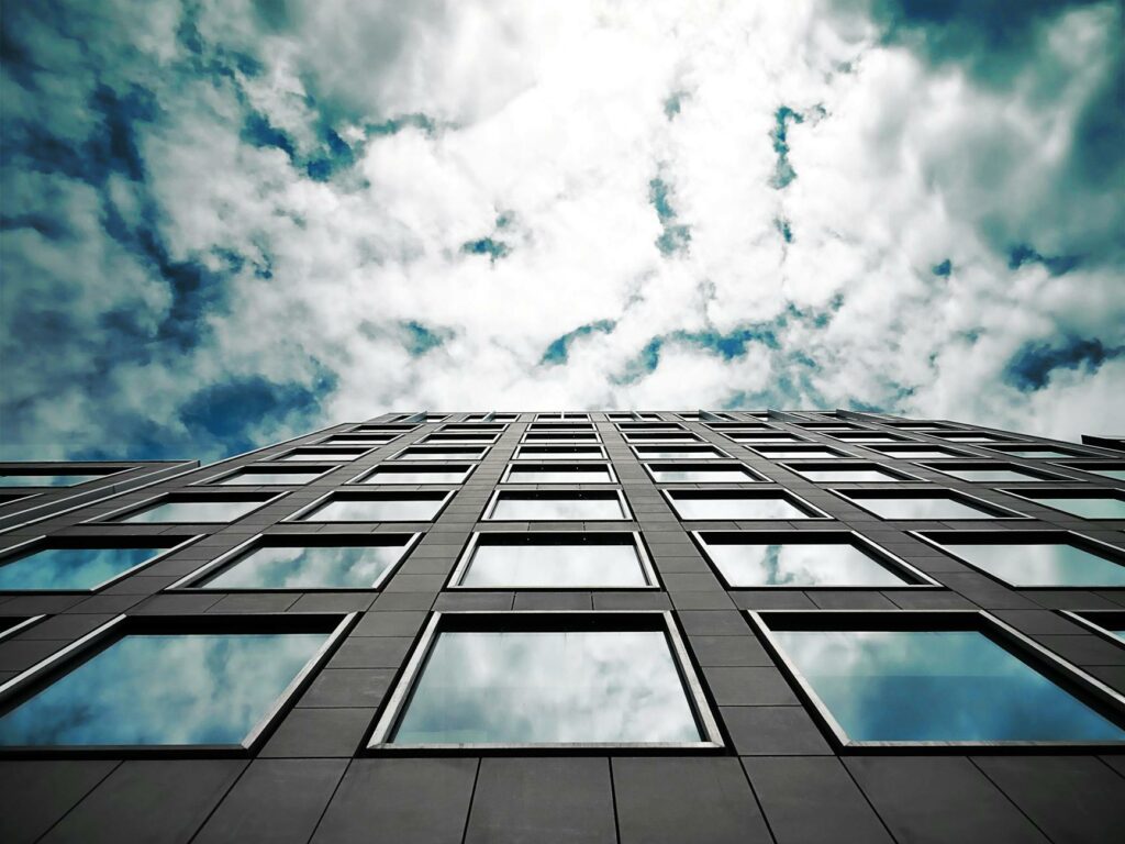 pexels-photo-569792-569792 Low angle of a modern skyscraper reflecting clouds in its glass windows with a dramatic sky.
